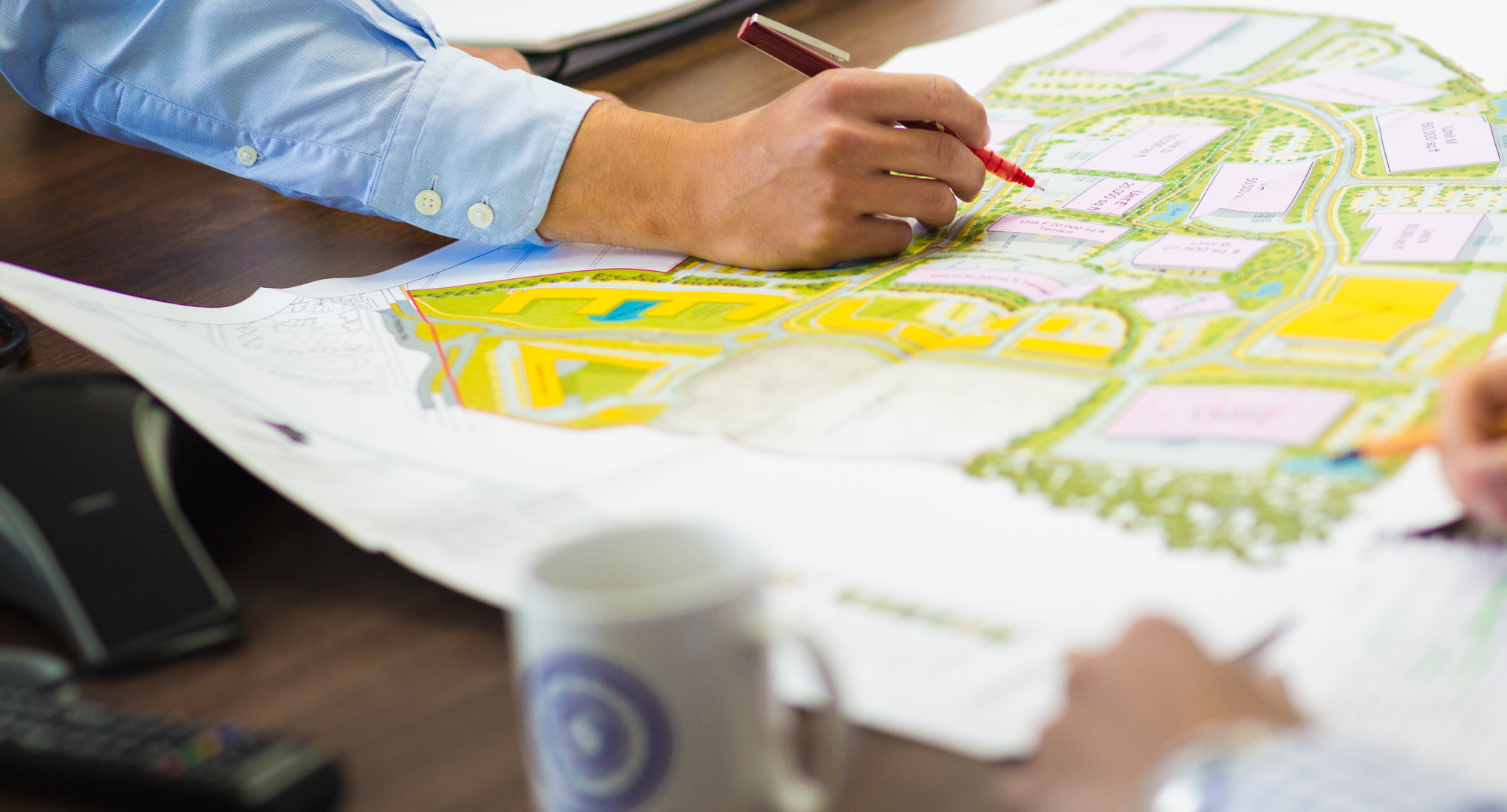 Person sketching ideas for land planning onto masterplan document.