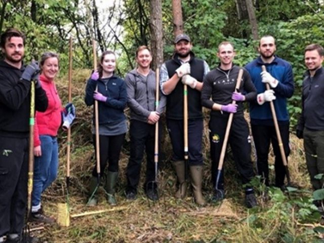 A group of people with various gardening tools such as spades, pitchforks and hoes.
