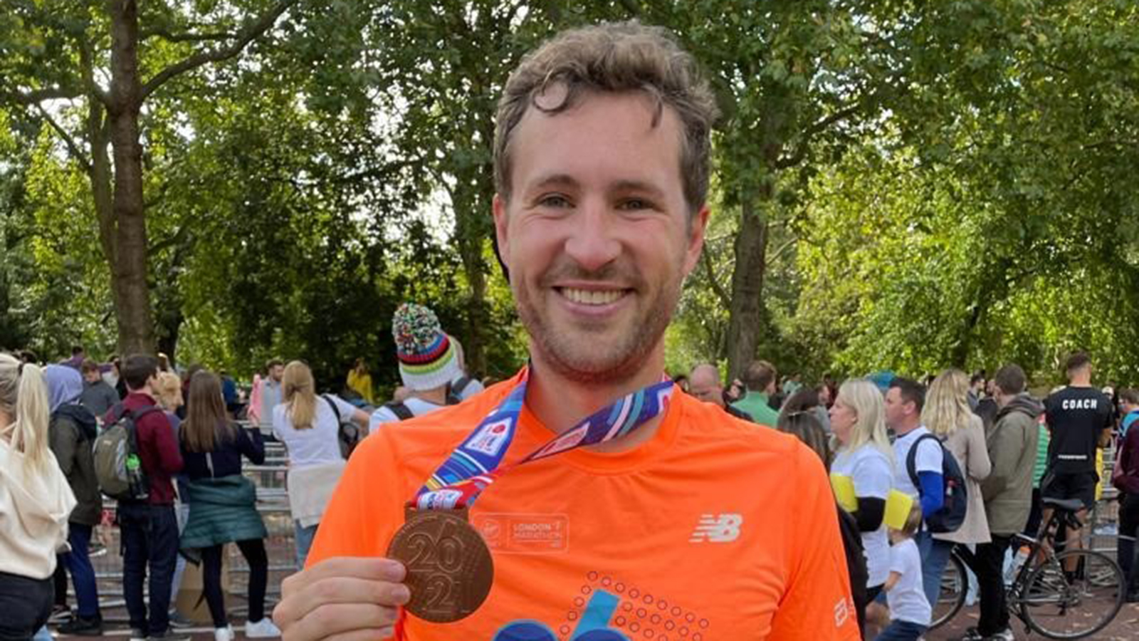 Man wearing running gear holding up medal with 2021 embossed on it.