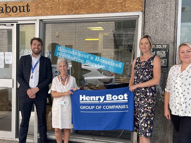 Henry Boot banner being held at the opening of a Roundabout Homeless Prevention Service.