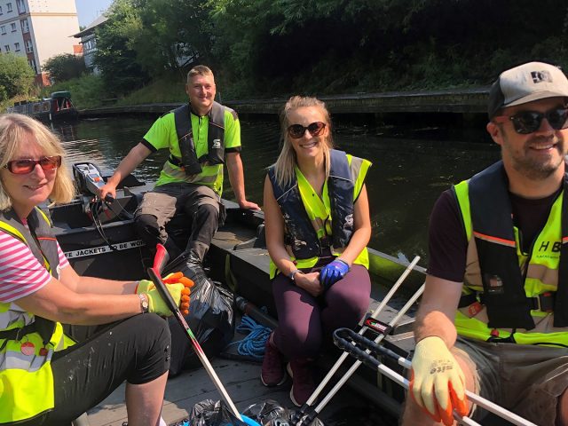 People smiling as they sail down a canal on a powered boat.