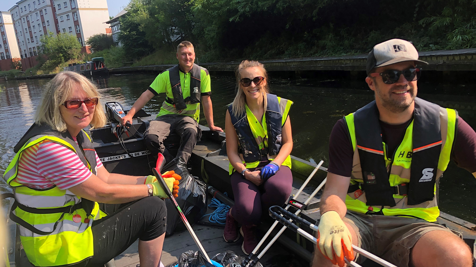 People smiling as they sail down a canal on a powered boat.