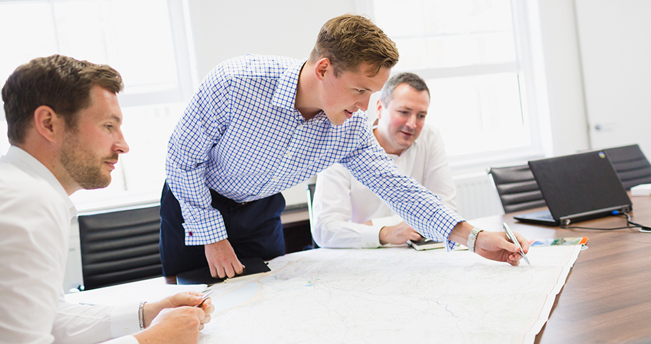 Land promoters discussing ideas in a meeting and sketching ideas onto a map.